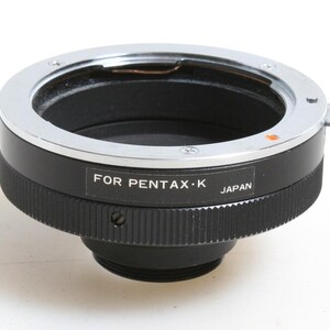May include: A black and silver camera lens adapter with the text "FOR PENTAX-K JAPAN" printed on the side.