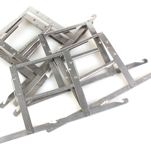 Puede incluir: Un conjunto de seis marcos de fotos de metal plateado con ganchos en los lados. Los marcos están apilados uno encima del otro.