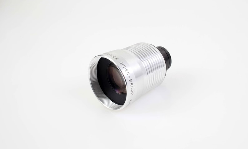 May include: A silver lens with the text "WAIFLEX SUPER-BRIGHT" is displayed against a white background. The lens has a black end and a ridged, cylindrical body. The lens is designed for photography.