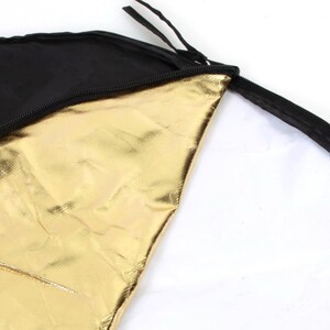 Könnte beinhalten: Ein schwarzer und goldener Fotoreflektor mit einem Reißverschluss-Trageetui. Der Reflektor besteht aus einem glänzenden, metallischen Material.