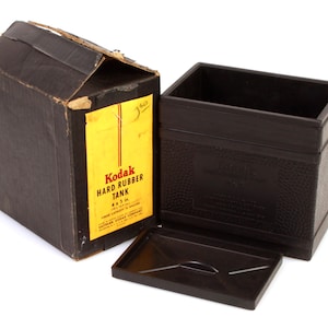 May include: A vintage Kodak Hard Rubber Tank for developing 4x5 in film. The tank is made of black hard rubber and comes in its original box.