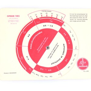 May include: A rectangular off-white Bolex Paillard exposure calculator card featuring a rotating red and white circular dial. The card displays technical text, filming speeds, and exposure times for various camera models including H8, H16, B8, and C8.