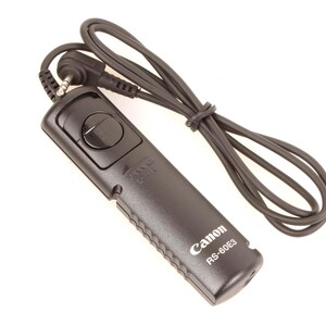May include: Black Canon RS-60E3 remote shutter release with a black cord. The remote has a button and is designed for cameras. The Canon logo and model number are visible on the device.