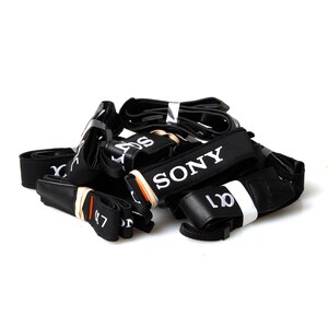 May include: A pile of black camera straps with white text. The straps have the words "SONY" and "a7" printed on them.