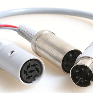 May include: A gray cable with two 8-pin DIN connectors. One connector is silver and the other is gray.