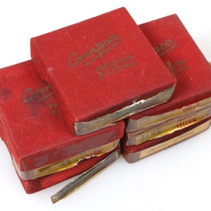 Puede incluir: Pila de seis cajas rojas con letras doradas. La caja superior dice "Coolidge Precision Filters". Las cajas de abajo están etiquetadas como "Amarillo", "Amarillo", "27 mm", "Verde" y "Verde".