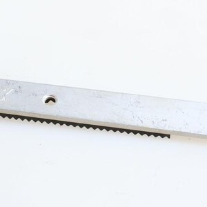 May include: A silver metal slide rail with a black toothed track, a round knob on one end, and a screw on the other end. The rail is labelled "F.A.M.A. Made in U.S.A."