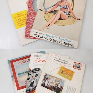 Puede incluir: Una colección de revistas vintage, incluyendo "U.S. Camera" y publicaciones de Kodak. Las revistas "U.S. Camera" presentan portadas con mujeres y contenido relacionado con la fotografía. Las revistas Kodak muestran ilustraciones de cámaras e información sobre procesamiento de fotos.