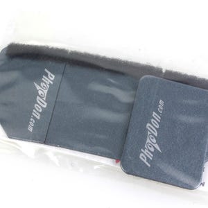 May include: Two gray, rectangular cleaning pads with the text "Phodon.com" printed in white. The pads are packaged in a clear plastic bag.