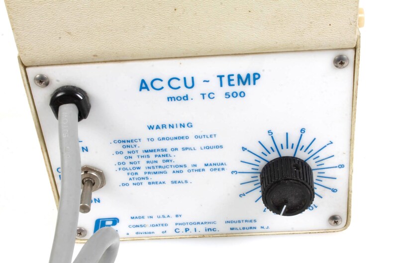 Pu&ograve; includere: Un pannello di controllo bianco con il testo "ACCU-TEMP mod. TC 500" e un'etichetta di avvertenza. Il pannello ha una manopola nera con un quadrante che va da 2 a 9. Il testo sull'etichetta recita: "CONNECT TO GROUNDED OUTLET ONLY. DO NOT IMMERSE OR SPILL LIQUIDS ON THIS PANEL. DO NOT RUN DRY. FOLLOW INSTRUCTIONS IN MANUAL FOR PRIMING AND OTHER OPERATIONS. DO NOT BREAK SEALS."