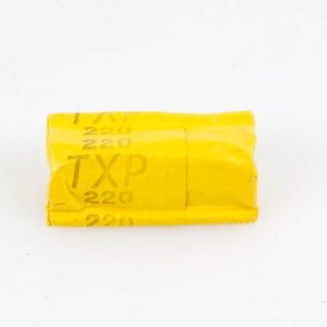 Peut inclure: Une boîte de film jaune vif avec le texte "TXP 220" imprimé sur le côté. La boîte est rectangulaire et semble être scellée. Le fond est blanc uni.
