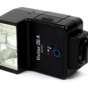 以下が含まれることがあります： 白いフラッシュヘッドとホットシューマウントを備えた、黒いVivitar 26A Autoフラッシュユニット。フラッシュには、AutoとMの設定を持つモードセレクタースイッチがあります。