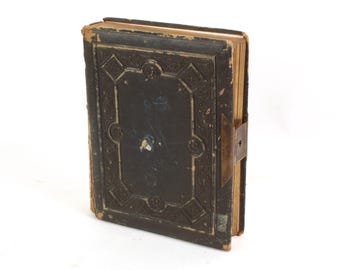 Puede incluir: Un álbum de fotos vintage encuadernado en cuero marrón oscuro con detalles dorados ornamentados y un cierre de latón.