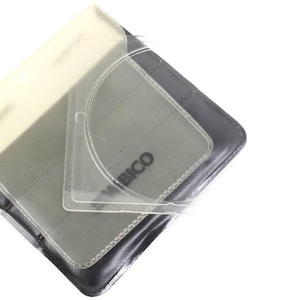 May include: A clear plastic CD case with a black leather cover. The case has a clear plastic window to view the CD. The cover has the word "BICO" printed on it.