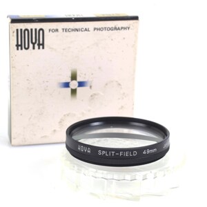 May include: A black Hoya Split-Field 49mm camera lens with a clear glass center, next to its original box. The box is off-white with the Hoya logo and text, "FOR TECHNICAL PHOTOGRAPHY".
