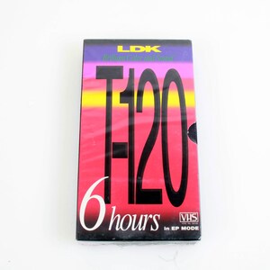 以下が含まれることがあります： ヴィンテージLDK T-120 VHSビデオカセットテープ。ラベルはピンク、黄色、紫などのグラデーションカラーです。「T-120」と「6時間」の文字が大きく表示されています。テープはSPモードです。