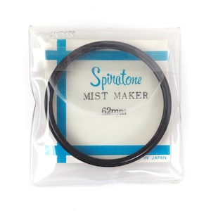 May include: A black Spiratone Mist Maker filter, 62mm, in a clear plastic package. The packaging has a white background with blue accents and the text "Spiratone MIST MAKER" in a teal font. The package is labeled "JAPAN".