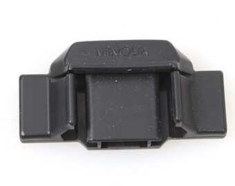 May include: Black plastic camera flash attachment with the word "MINOLTA" printed on the top.