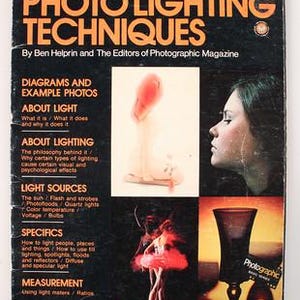 Puede incluir: Un libro de tapa blanda titulado Petersen's Guide to Photo Lighting Techniques de Ben Helprin y los editores de Photographic Magazine. La portada negra presenta texto naranja, el perfil de una persona, una bailarina y una copa.