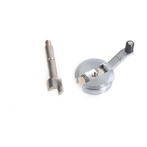 Puede incluir: Dos herramientas metálicas sobre fondo blanco. Una es una herramienta circular plateada con un mango y una punta negra. La otra es una herramienta cilíndrica plateada con un extremo bifurcado.