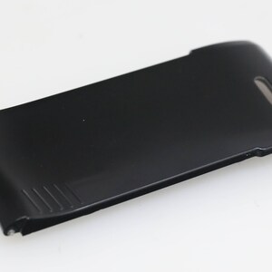 May include: Black plastic phone case with a curved design and a small hole on the top.