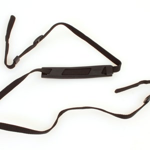 May include: Black camera strap with a padded handle. The strap has adjustable lengths and is made of durable nylon.