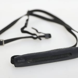 May include: Black camera strap with a padded shoulder rest. The strap has a Canon logo and the text "Japan" printed on it.