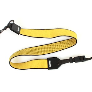 May include: Yellow camera strap with black accents and the word "hama" printed on the strap.