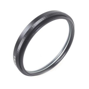May include: A black circular camera lens filter with a ridged outer edge. The filter has a clear glass centre and is designed to attach to a camera lens. The filter is likely used to protect the lens or modify the image.