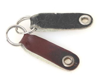 May include: Two leather keychains with metal rings. One keychain is brown and the other is black.