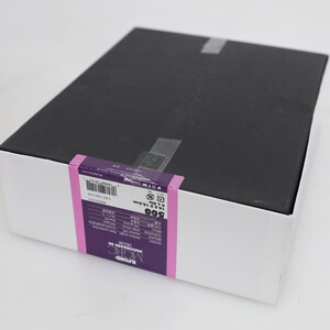 以下が含まれることがあります： 黒色の蓋が付いた白い箱。箱には、「ILFORD MULTIGRADE FB」と「500」の文字が印刷された紫と白のラベルが付いています。ラベルには、バーコードと製品に関するその他の情報も含まれています。