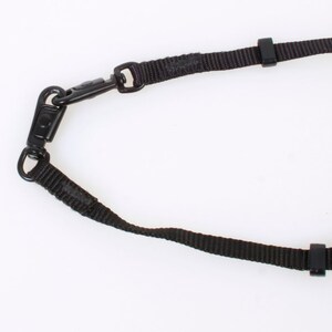 Peut inclure: Une sangle de caméra noire avec deux boucles réglables et un clip en métal.