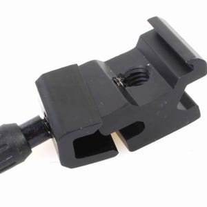 May include: Black metal camera flash bracket with a screw and a knob. The bracket has a cold shoe mount and a 1/4-inch screw hole.