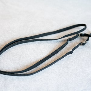 Puede incluir: Una correa de cámara negra con dos hebillas ajustables.