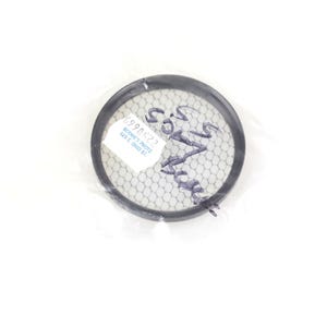 Könnte beinhalten: Ein kreisförmiger Kameraobjektivfilter mit schwarzem Rand und einem feinen Netzmittelteil. Der Filter ist mit handschriftlichem Text und einem Aufkleber mit gedruckten Informationen versehen. Der Filter ist in klarem Kunststoff verpackt.