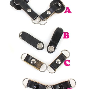 以下が含まれることがあります： 金属製のリングが付いた革製のキーホルダーが4種類あります。キーホルダーは黒と茶色の革製で、金属製の鋲とハトメが付いています。キーホルダーはA、B、C、Dとラベル付けされています。