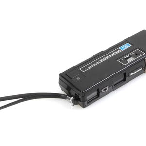 May include: A black Keystone 120 pocket everflash camera with a built-in flash and a black wrist strap.