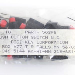 May include: A clear plastic bag containing ten black push button switches with red button tops. The label reads "PUSH BUTTON SWITCH N.C." and includes the Digi-Key Corporation information.
