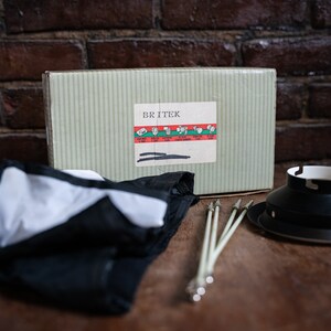 Könnte beinhalten: Ein weiß-schwarzer Stoff-Softbox mit einer grün-weißen Box mit der Aufschrift "BRITEK" und einem schwarzen Metallreflektor. Die Box enthält ein Diagramm verschiedener Beleuchtungseinstellungen.