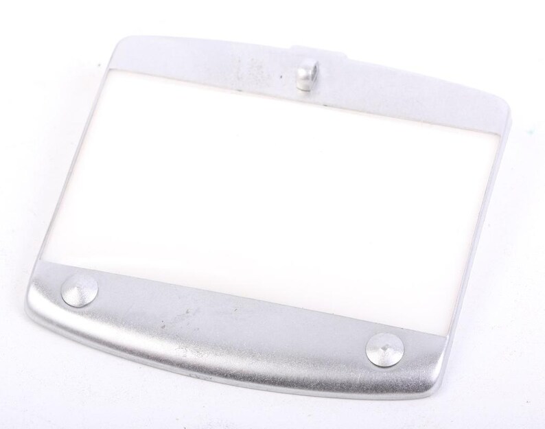 May include: A rectangular, silver-colored light fixture with a white, translucent center. The fixture has rounded edges and two circular rivets on the bottom. A small, raised loop is centered on the top edge.