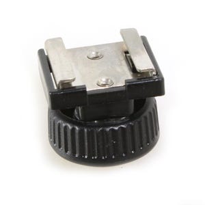 Puede incluir: Un adaptador de zapata de flash negro y plateado con una base roscada.