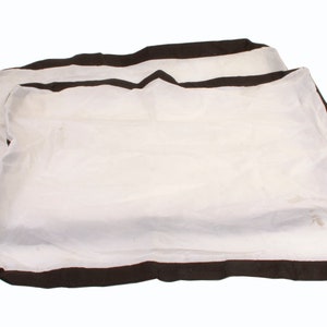 Op de afbeelding: Twee witte kussenslopen met een donkerbruine rand. De kussenslopen zijn gemaakt van een dunne, lichtgewicht stof. De kussenslopen zijn op elkaar gestapeld.