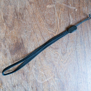 May include: A black camera strap with a small black loop at one end.