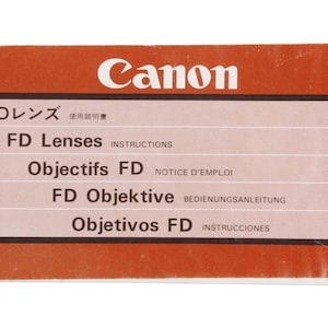 May include: A red and white Canon FD lens instruction manual with the text "FD Lenses" in English, "Objectifs FD" in French, "FD Objektive" in German, and "Objetivos FD" in Spanish.