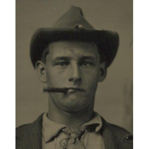 Può includere: Ritratto in seppia di un uomo con cappello da cowboy e cravatta fantasia, con un sigaro in bocca. L'uomo guarda direttamente la fotocamera. Fotografia d'epoca.