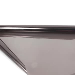 May include: A roll of tinted window film, partially unrolled, against a white background. The film is a dark gray color and appears to be reflective. The roll is cylindrical, and the unrolled portion lies flat.