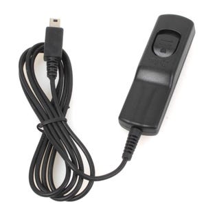 May include: A black camera remote shutter release with a black cable and a USB connector. The remote has a button on the top and is designed to control a camera's shutter.