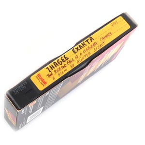 May include: A black Kodak video tape box with a yellow label. The label reads "IHAGEE EXAKTA" and "THE RISE AND FALL OF A LEGENDARY CAMERA". The box is labeled "2001" and "XT-120".