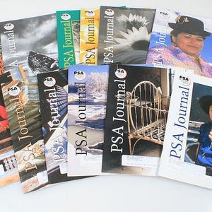 以下が含まれることがあります： さまざまな表紙画像が特徴のPSA Journalマガジンのコレクション。表紙には、人々、風景、オブジェクトの写真が掲載されています。雑誌は扇状に配置されており、コンテンツの多様性を示しています。