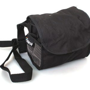 Peut inclure: Sac de caméra noir avec une poche en filet et le mot "Polaroid" imprimé sur le côté. Le sac a une sangle réglable.